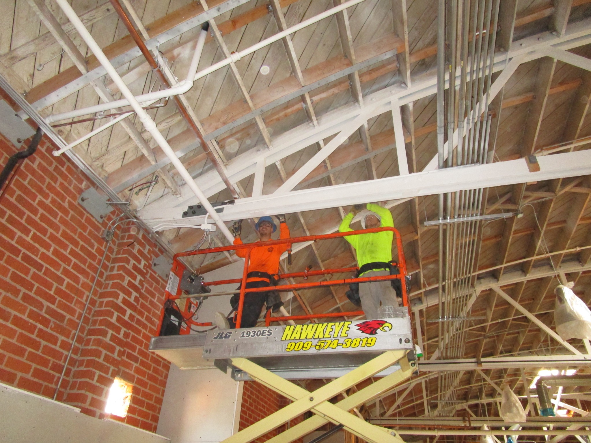 SPS crew working from an aerial lift beneath wood roof framing